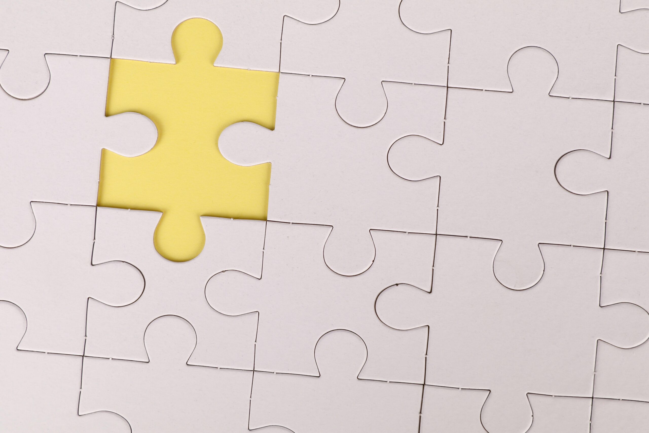 pexels-photo-3482442-3482442 Close-up of a white jigsaw puzzle with a single yellow piece missing, symbolizing incompleteness.